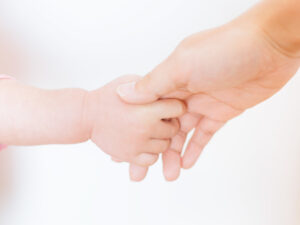 赤ん坊の手と繋がる母親の手